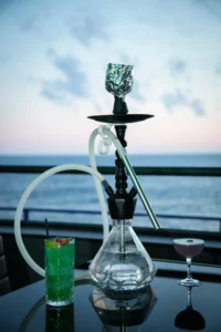 Traditional hookah pipe served with refreshing colorful cocktail drinks on a table.